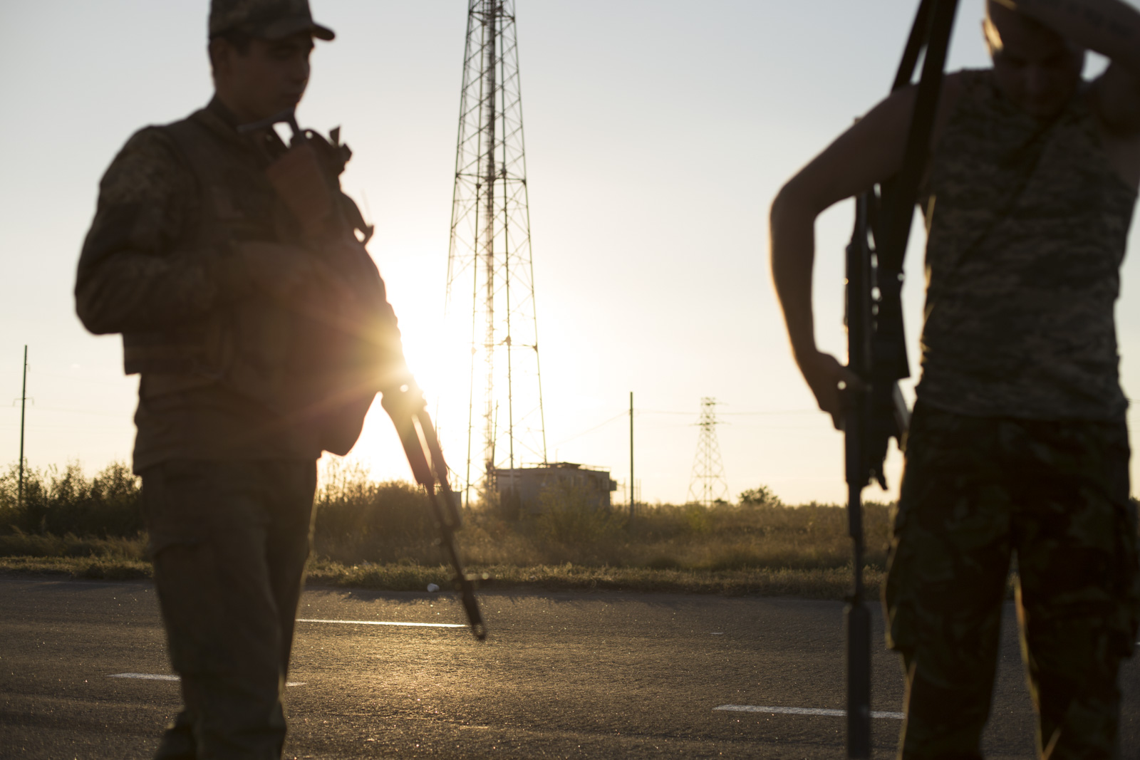 Two soldiers silhouetted against a sunset prepare to patrol the donbas region.