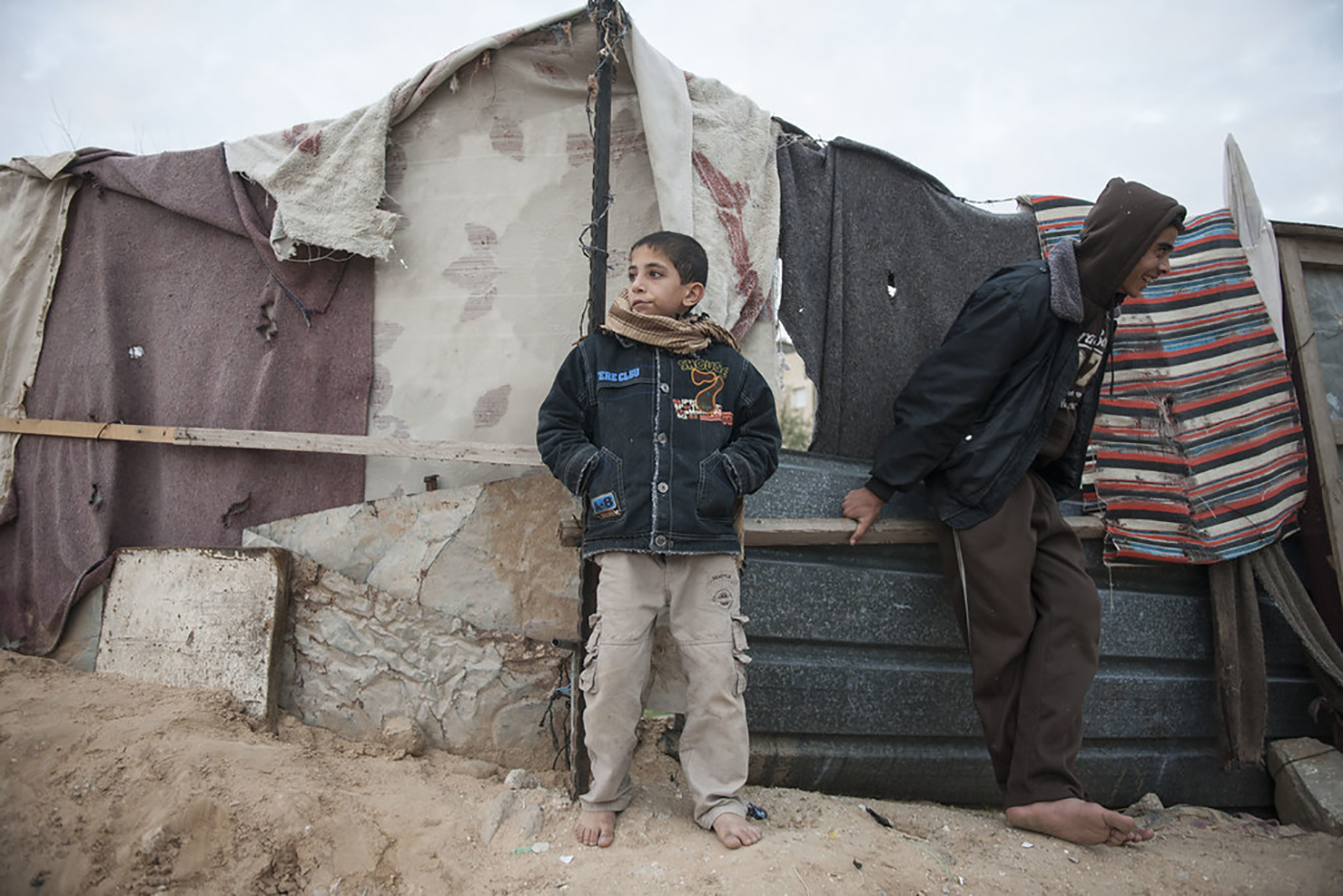 A young Palestinian boy stands against a wall at the Gaza blockade bordering Egypt.