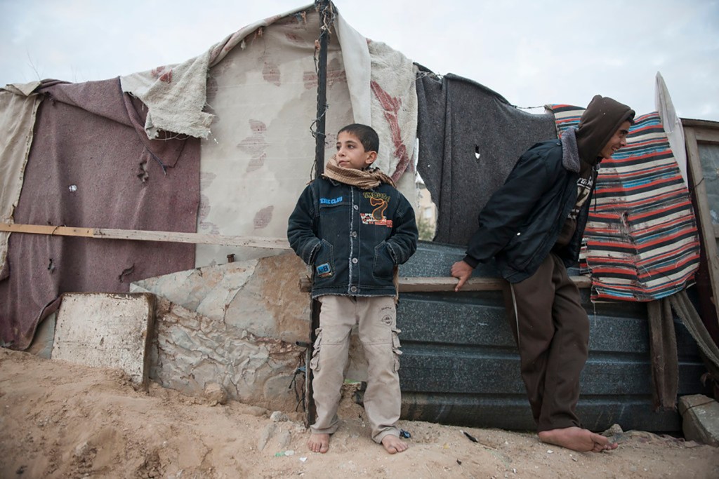 A young Palestinian boy stands against a wall at the Gaza blockade bordering Egypt.