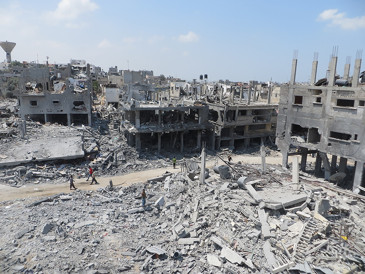 A destroyed building surrounds people walking in amongst it.