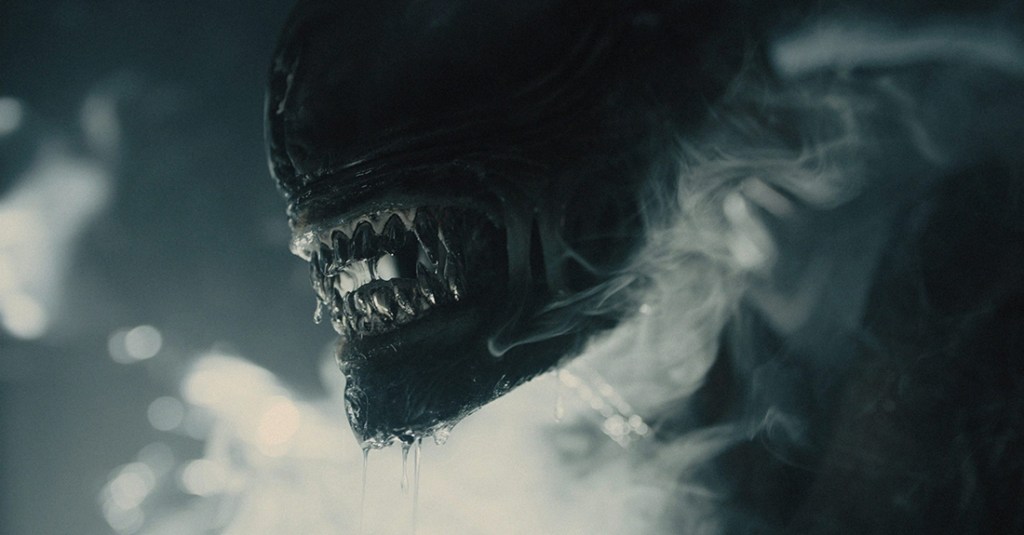 An xenomorph stares out from a smokey background.