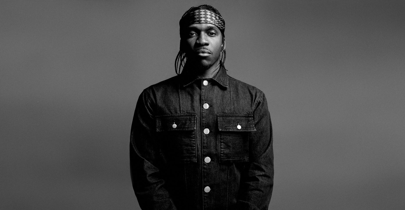 Press photo of Pusha T in black and white. He is wearing a black denim jacket and bandana.