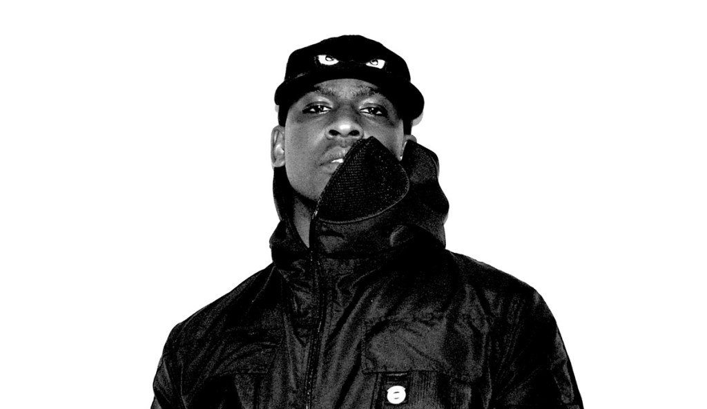 Rapper Skepta picrtured against a white backdrop wearing a black cap and jacket.