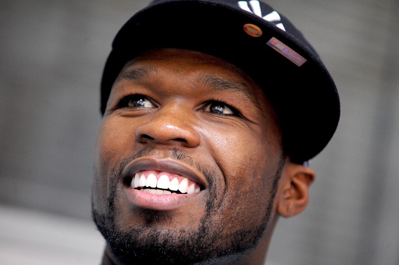 Rapper 50 Cent smiling during a press event.