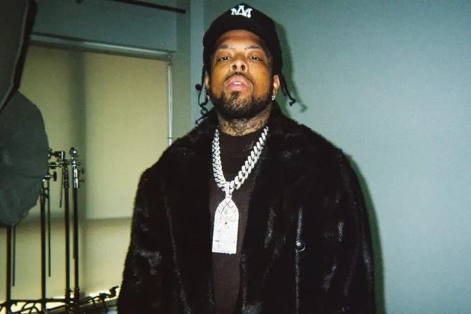 Westside Gunn wearing a platinum chain, black jacket, and cap in a promotional photograph for his album Heels Have Eyes 3.
