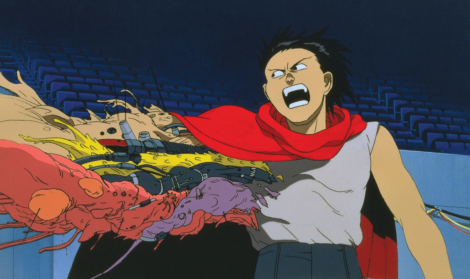 A still from the fan-favourite anime Akira (1988) showing Tetsuo undergoing a psychic mutation, with fleshy, mechanical appendages growing from his arm in a stadium setting.
