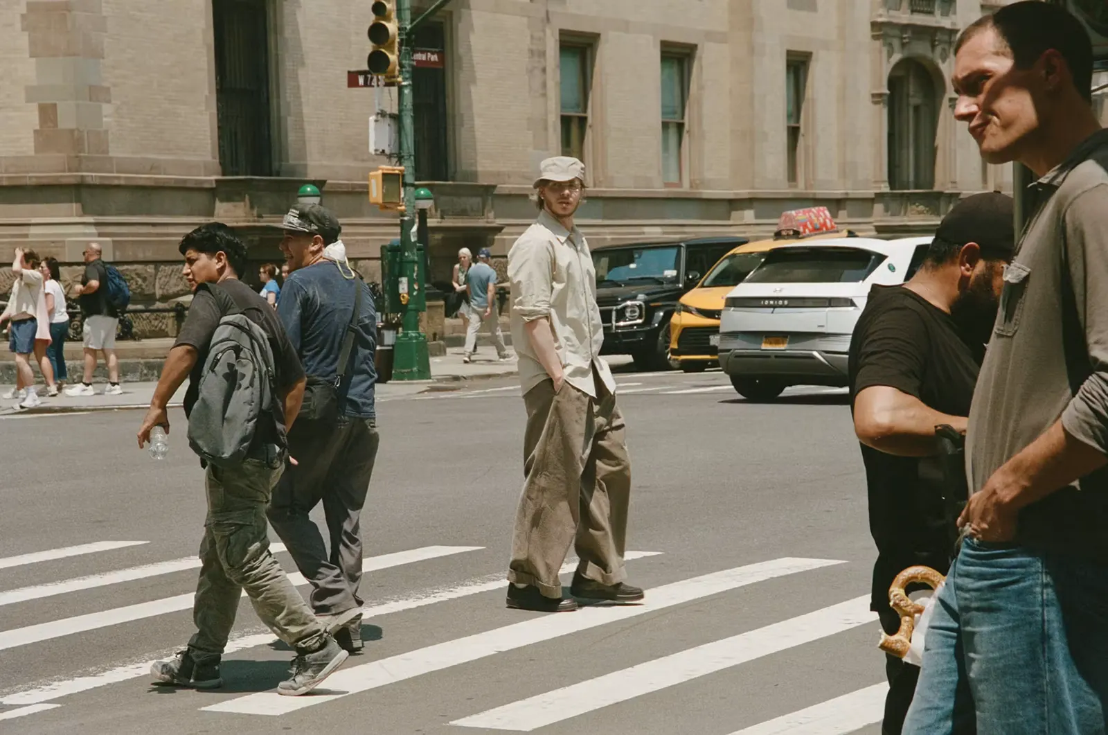 Jack Harlow walks across the street wearing his soon-to-drop New Balance T500 “Olmsted” sneakers.