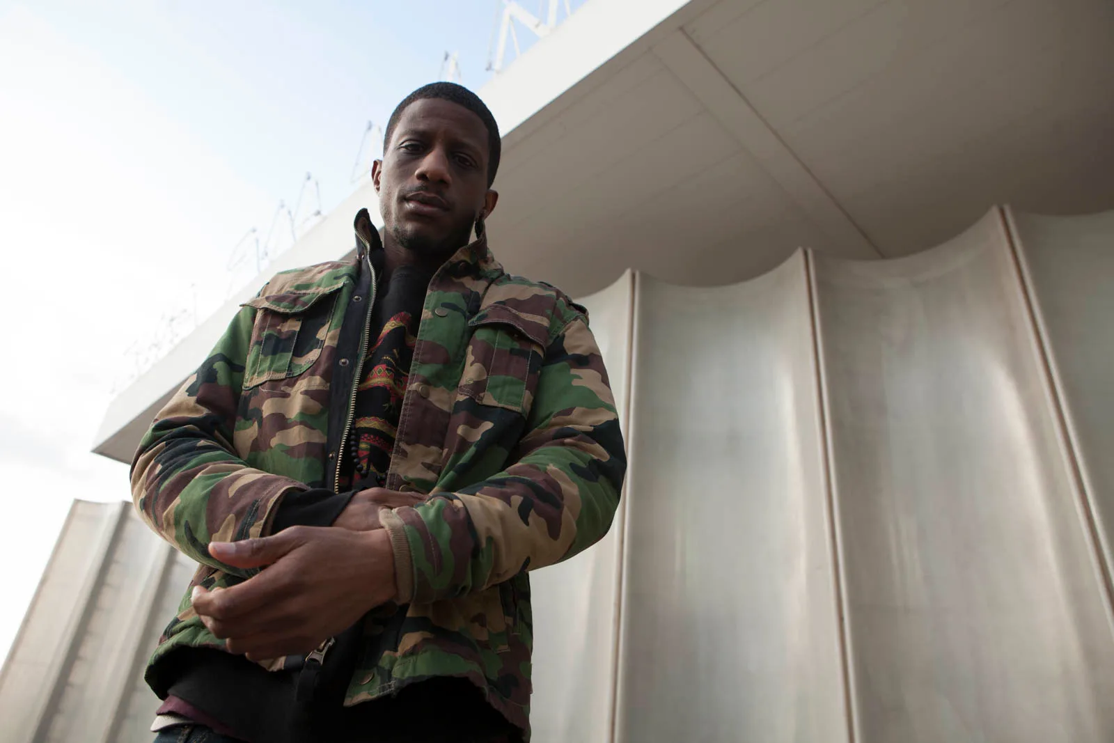 Melanin 9 wearing a camo jacket in a promotional photo for his album.