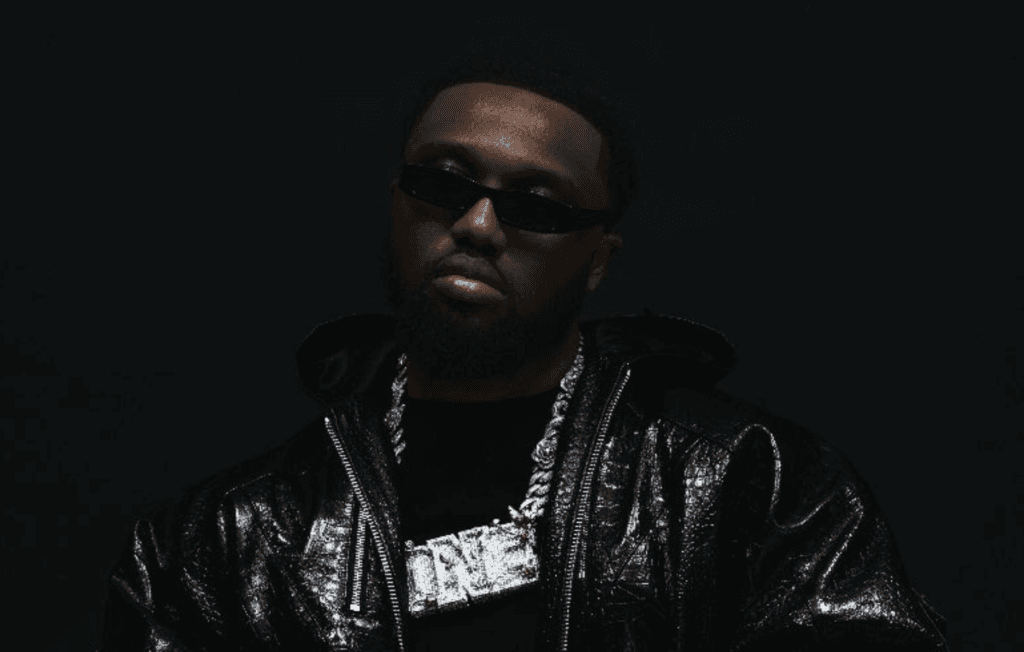 Headie One pictured wearing a black leather jacket and sunglasses in a promotional photo for his new mixtape, MMM.