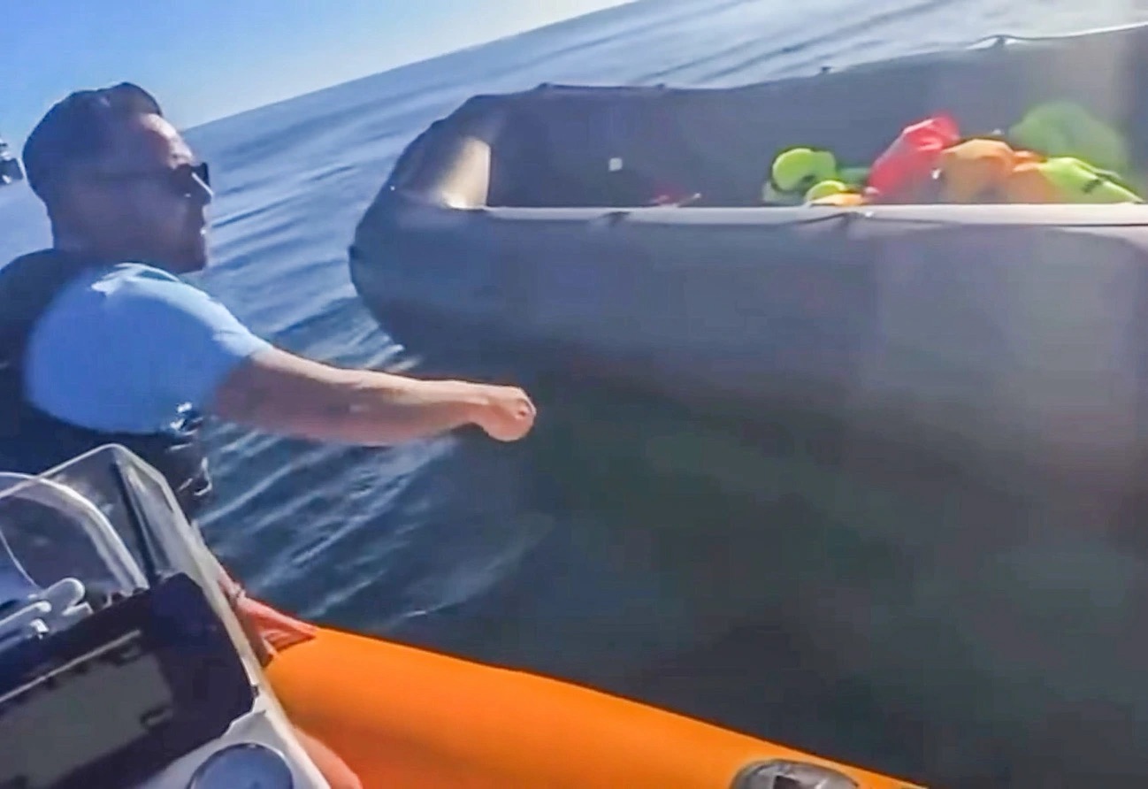 Danny Tommo reaches towards an inflatable dinghy from another boat in the English Channel.