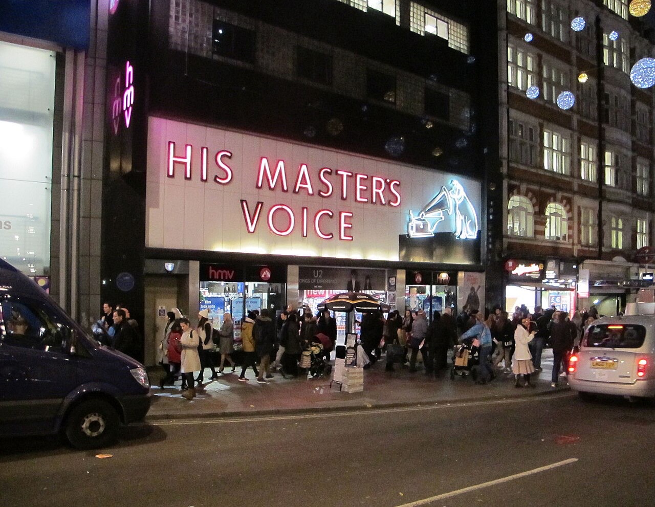 Illuminated exterior of HMV’s Oxford Street store in London, with lights decorating the street.